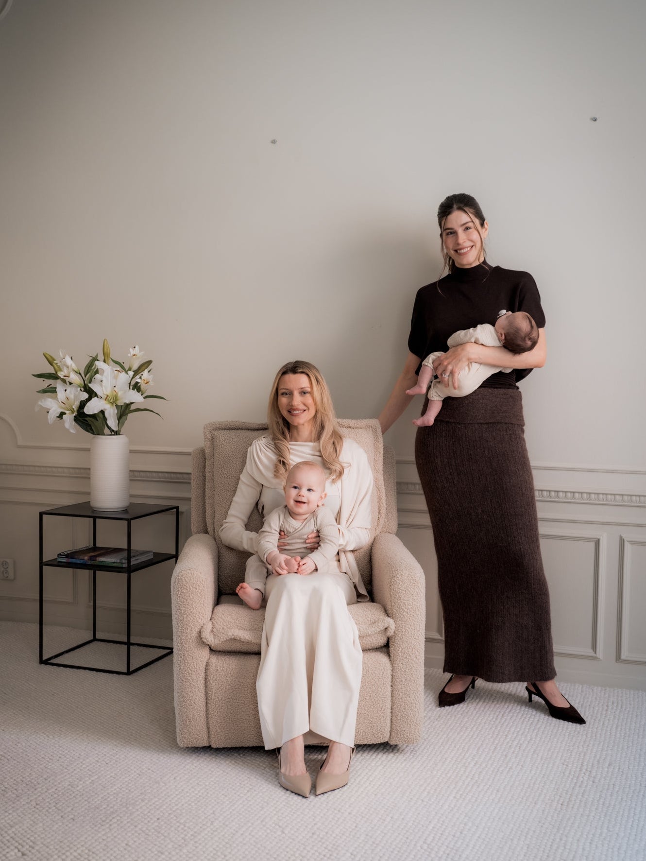 Two women with a baby and toddler in a room with decorative elements.