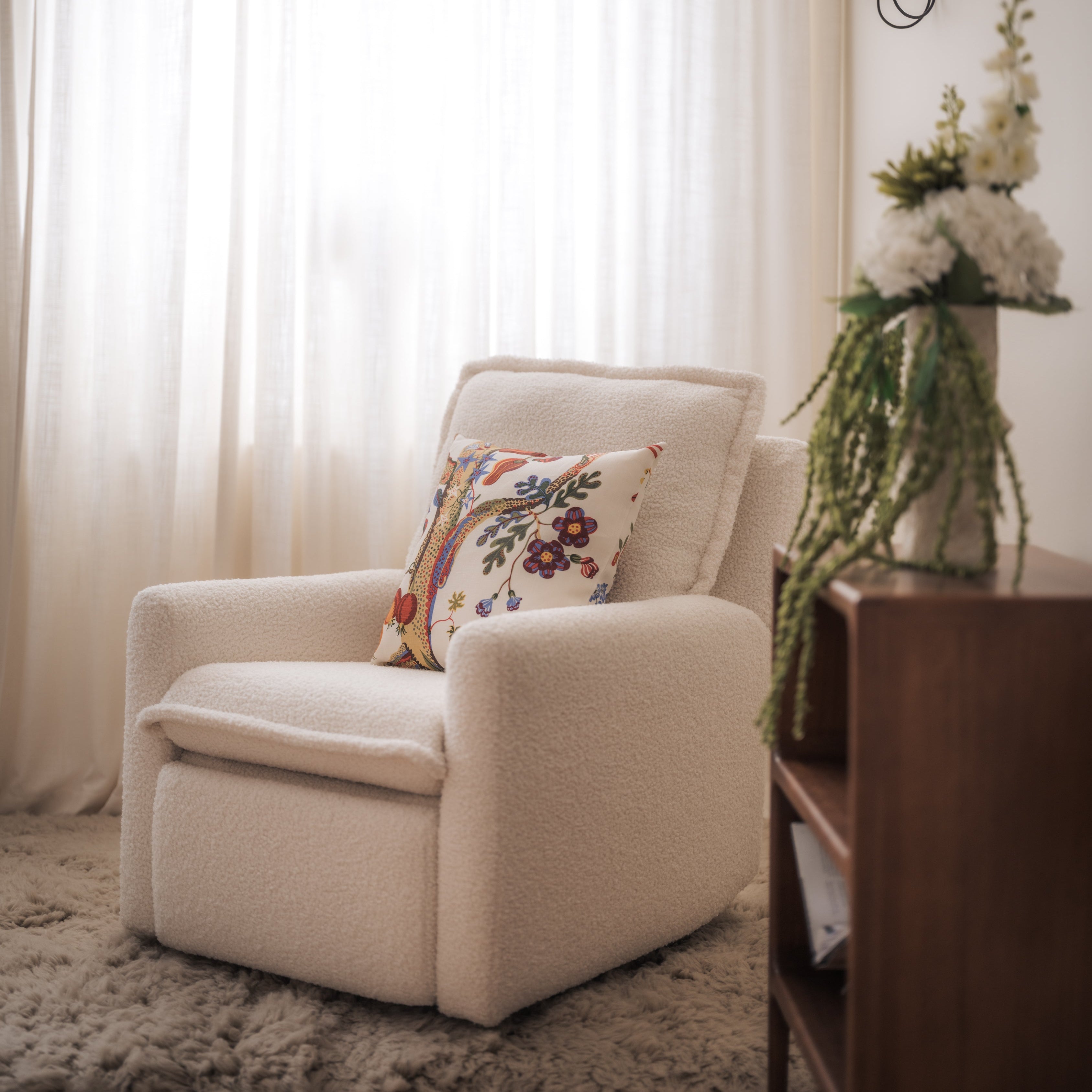 White armchair with a floral pillow in a living room setting