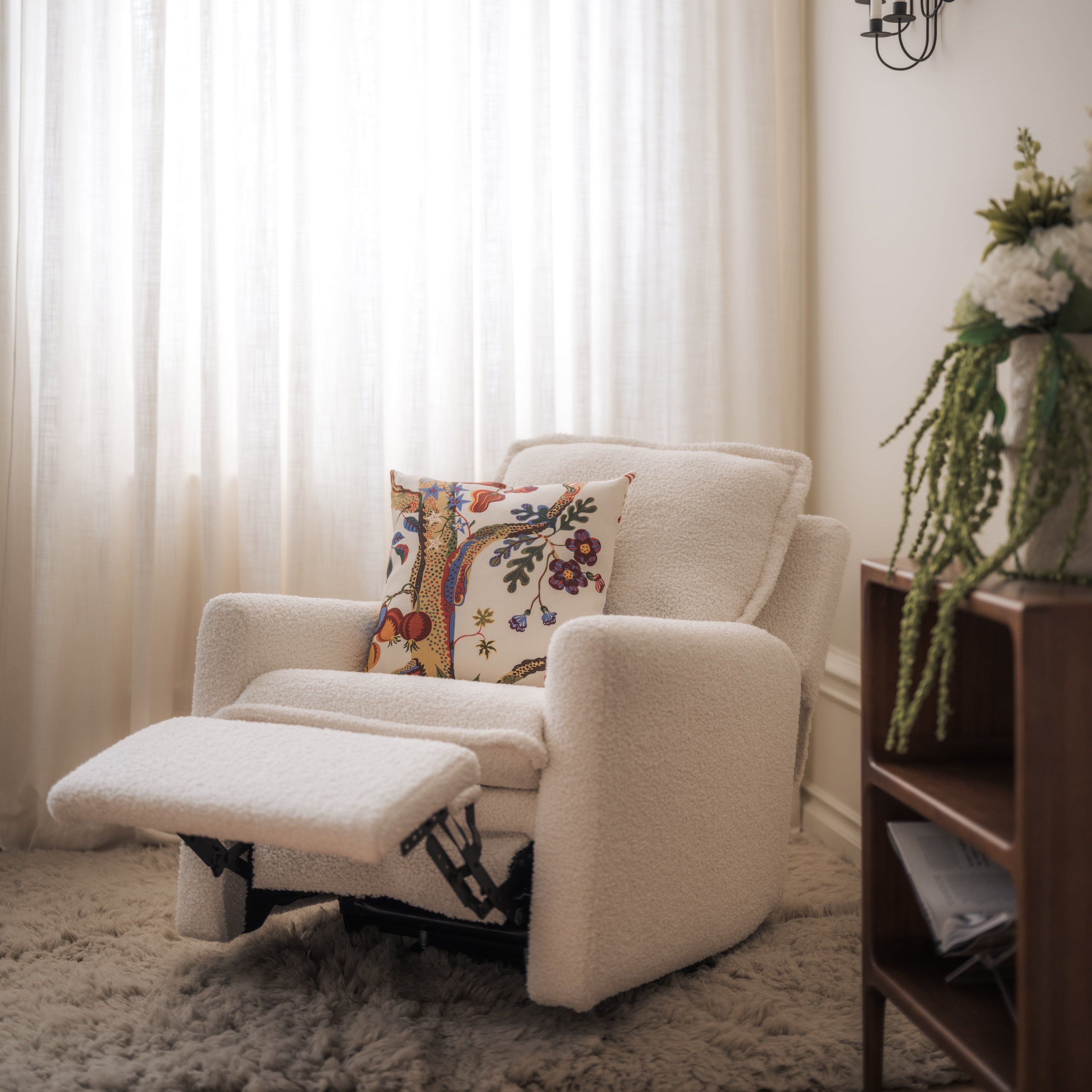 White recliner chair with a colorful pillow in a living room setting.
